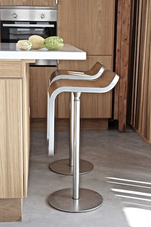 A kitchen with a white countertop, two stainless steel bar stools, and a wooden cabinet. - Holiday Home 'Casa Opala Townhouse with Pool' , Wi-Fi and Air Conditioning (Olhão)