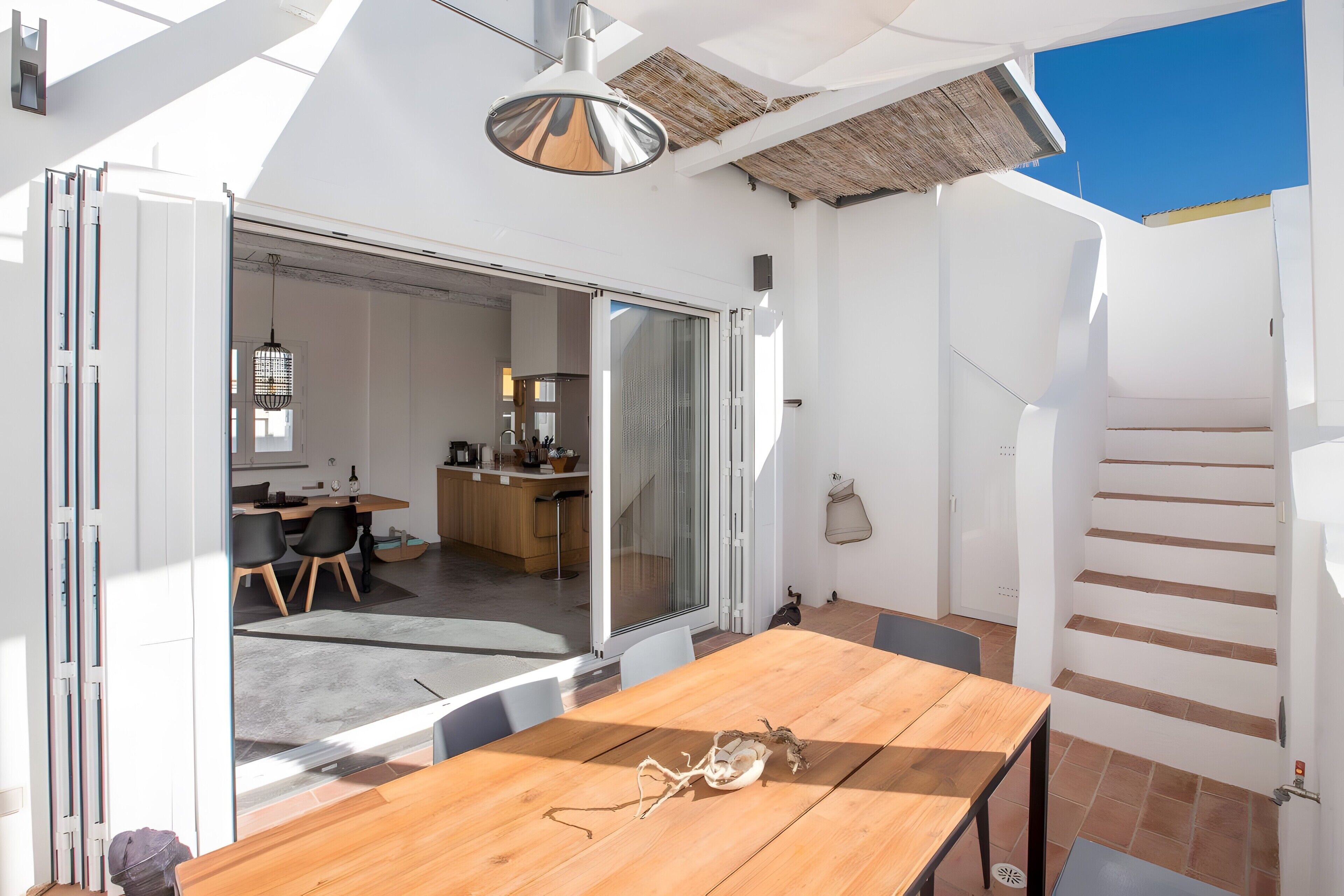 A modern kitchen with a dining area, a staircase, and a view of the outside.