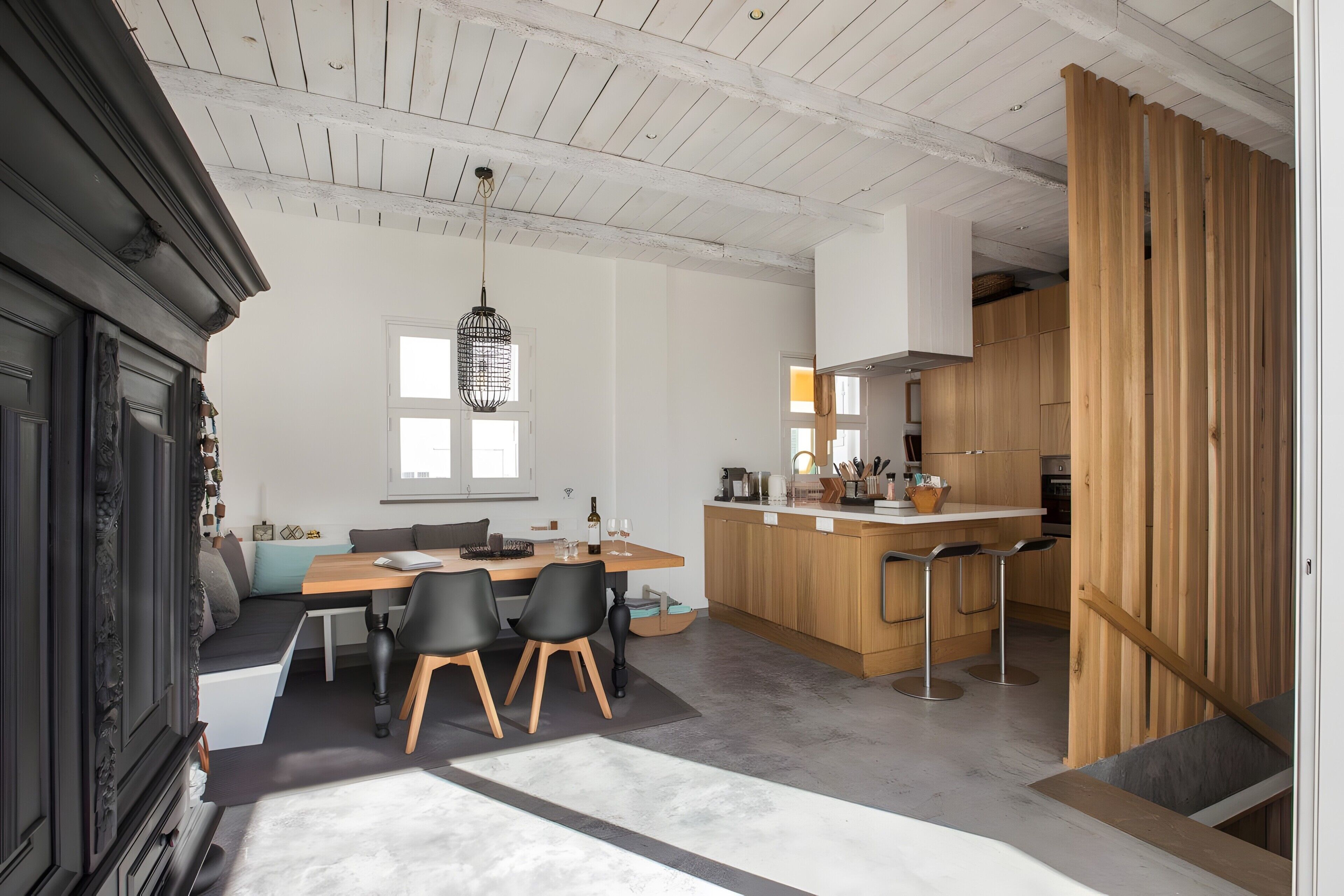 Una cocina moderna con armarios de madera, una barra y un comedor con mesa y sillas.