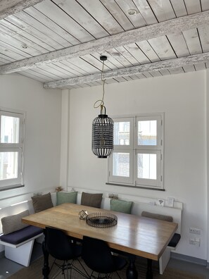 Ein Essbereich mit einem Holztisch, schwarzen Stühlen und einer hängenden schwarzen Leuchte.