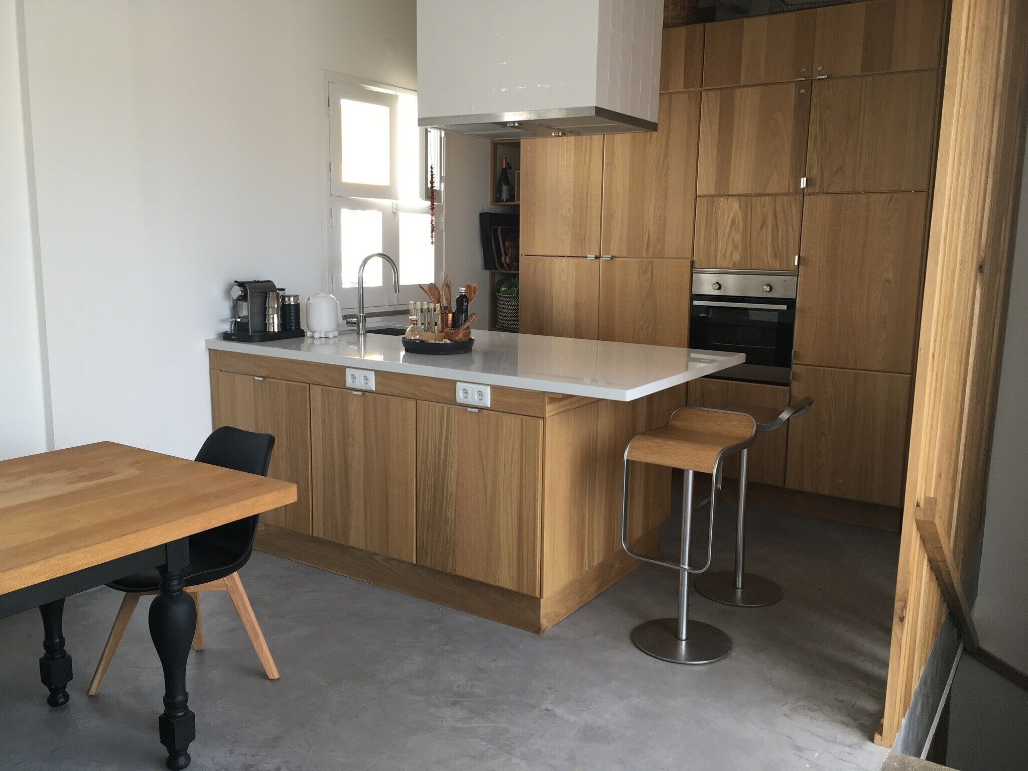 A modern kitchen with wooden cabinets, a stainless steel oven, and a bar stool.
