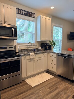 A kitchen with white cabinets, a stainless steel microwave, a dishwasher, and a countertop with a plant. - Salt & Serenity on 30A Walk to Santa Rosa Beach! 
CLEAN, 1st Floor Unit (Santa Rosa Beach,)