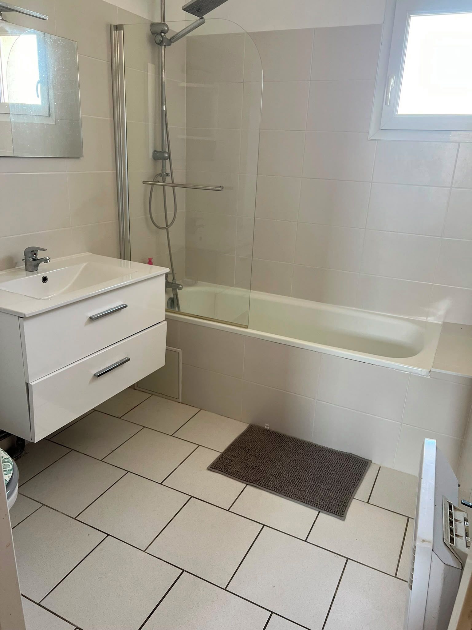 Un baño con lavamanos blanco, espejo, ducha y bañera.