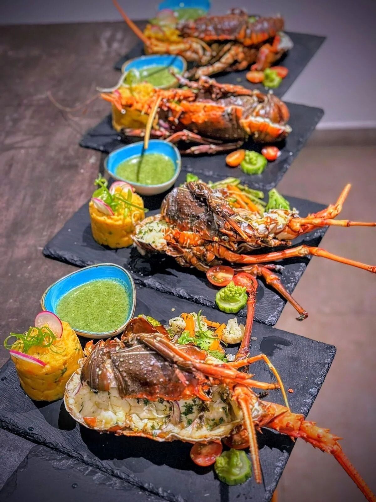 A seafood platter with multiple lobsters and sides of vegetables and sauces.