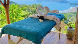Une table de massage offrant une vue sur l’océan et les collines.