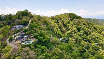 A hillside property with multiple buildings, a swimming pool, and a winding path.