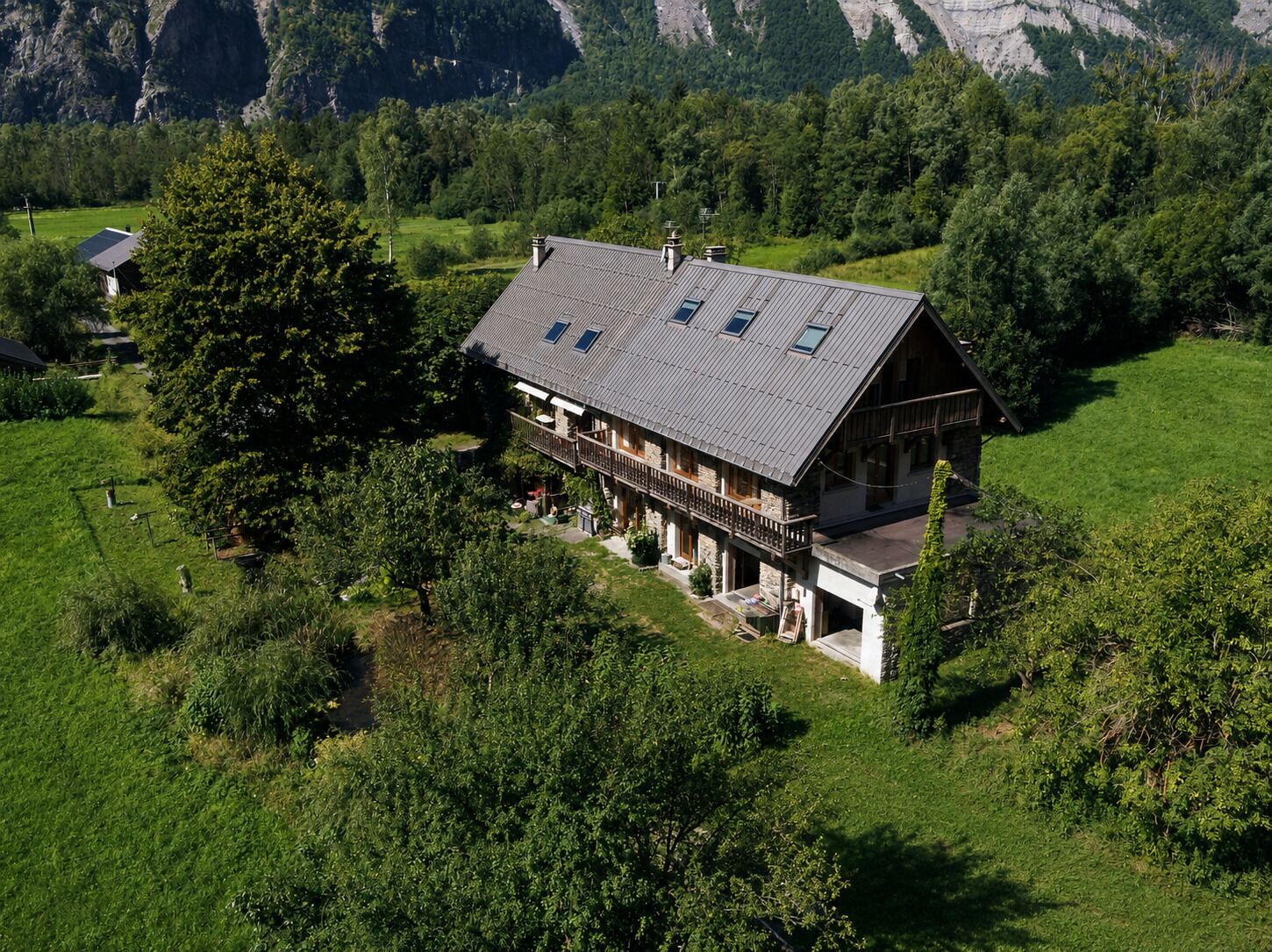 A two-story house with a sloped roof, a balcony, and a stone foundation.