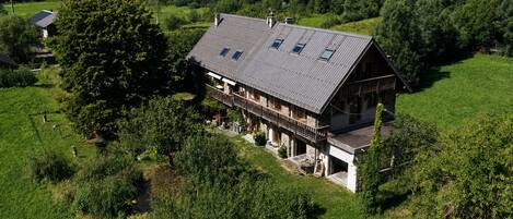 A two-story house with a sloped roof, a balcony, and a stone foundation.