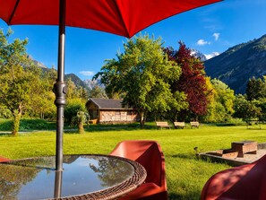A patio with a table and chairs, a red umbrella, and a view of a mountain landscape. - L'Alpin, an apartment in the heart of the Domaine de la Grande Longe in Oisans (Le Bourg-d'Oisans)