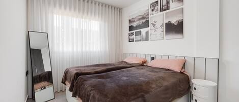 Ein Schlafzimmer mit zwei Betten, einem Spiegel, einem Nachttisch und einer Wand mit gerahmten Bildern.