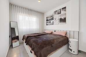 Ein Schlafzimmer mit zwei Betten, einem Spiegel, einem Nachttisch und einer Wand mit gerahmten Bildern.