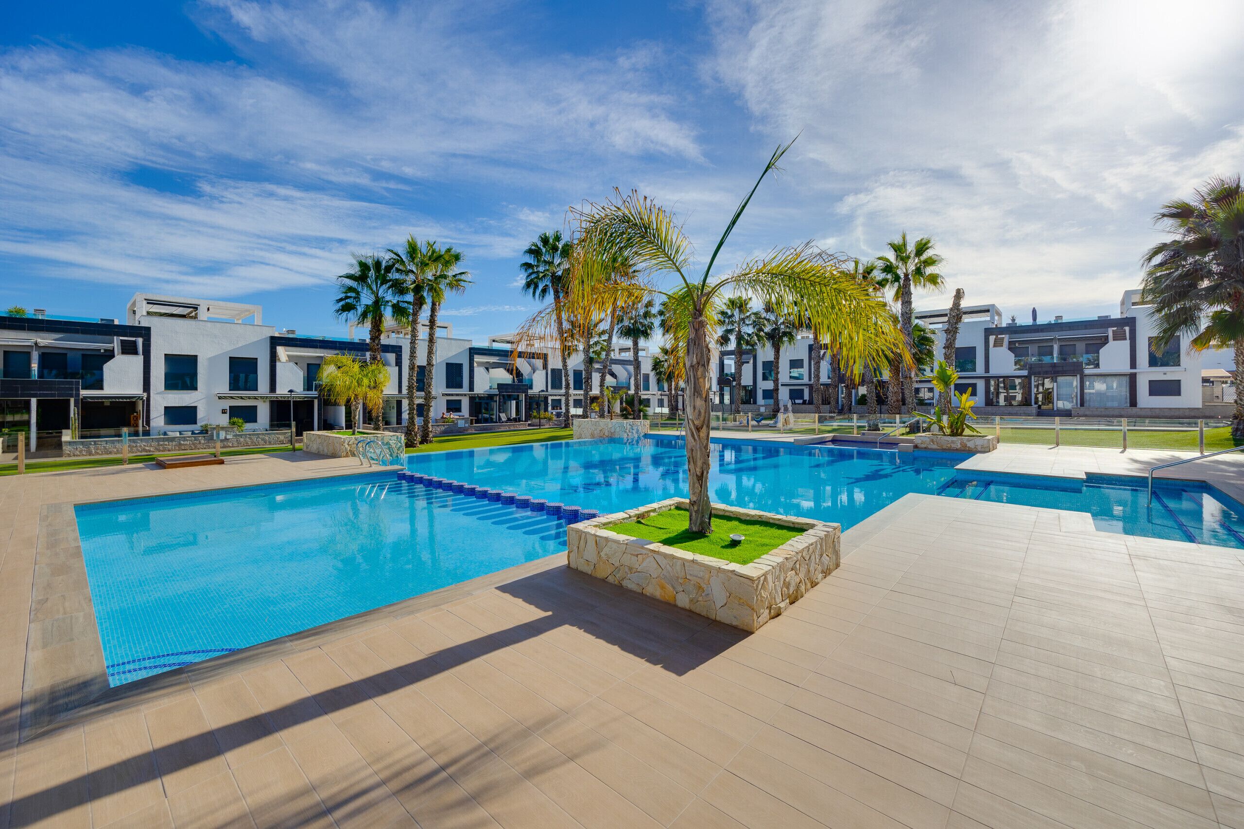 Ein modernes Hotel mit großem Pool, Palmen und moderner Architektur.