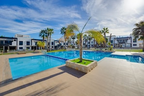 Ein modernes Hotel mit großem Pool, Palmen und moderner Architektur.