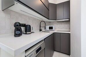 A modern kitchen with a built-in microwave, a coffee maker, and a dishwasher. - CB Living - Seaview penhouse in Cabo Roig (Orihuela)