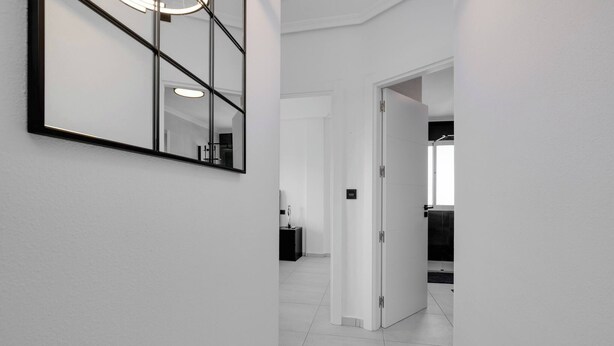 A hallway with a large mirror, a door leading to a bathroom, and a tiled floor. - CB Living - Seaview penhouse in Cabo Roig (Orihuela)