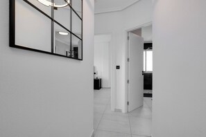 A hallway with a large mirror, a door leading to a bathroom, and a tiled floor. - CB Living - Seaview penhouse in Cabo Roig (Orihuela)