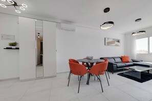 Un salon moderne comprenant un coin repas, un canapé en cuir noir et une table basse en verre.