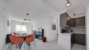A modern kitchen with dark cabinets and a white countertop. - CB Living - Seaview penhouse in Cabo Roig (Orihuela)