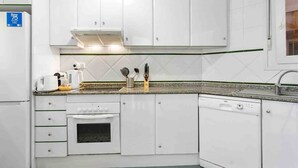 A kitchen with white cabinets, a built-in oven, a dishwasher, and a coffee maker.
