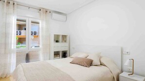 A bedroom with a bed, bedside table, and a window with curtains.