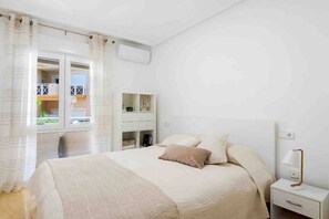 A bedroom with a bed, bedside table, and a window with curtains. - CB Living- Beachfront apartment Aquamarina (Orihuela)