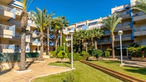A residential building with multiple balconies, palm trees, and a well-maintained lawn.