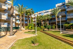 A residential building with multiple balconies, palm trees, and a well-maintained lawn. - CB Living- Beachfront apartment Aquamarina (Orihuela)
