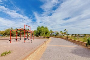 An outdoor exercise area with a red metal structure, paved walkways, and greenery. - CB Living- Beachfront apartment Aquamarina (Orihuela)