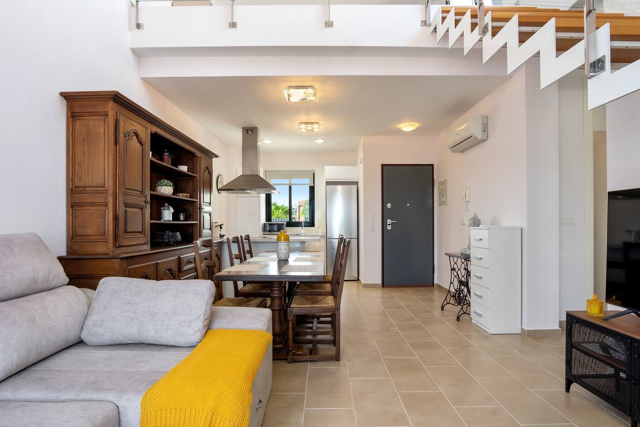 A modern living room with a sofa, dining table, and kitchen area.