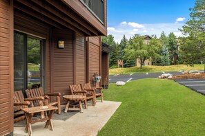 Ein Holzgebäude mit einer Terrassenfläche, die Sitzgelegenheiten im Freien und einen gepflegten Rasen bietet.