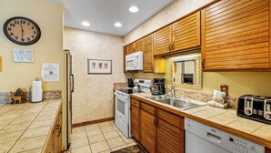 Una cocina con armarios de madera, microondas, estufa y lavavajillas.