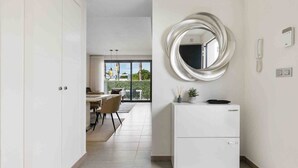 A modern kitchen with a white refrigerator, a round mirror, and a dining area with a table and chairs. - CB Living - 3 bedroom home in Punta Prima (Alicante / Alacant)