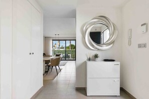 Eine moderne Küche mit einem weißen Kühlschrank, einem runden Spiegel und einem Essbereich mit Tisch und Stühlen.