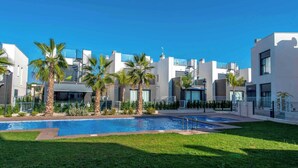 A modern residential complex with a swimming pool, palm trees, and contemporary architecture. - CB Living - 3 bedroom home in Punta Prima (Alicante / Alacant)
