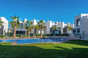 Ein moderner Wohnkomplex mit Schwimmbad, Palmen und zeitgemäßer Architektur.