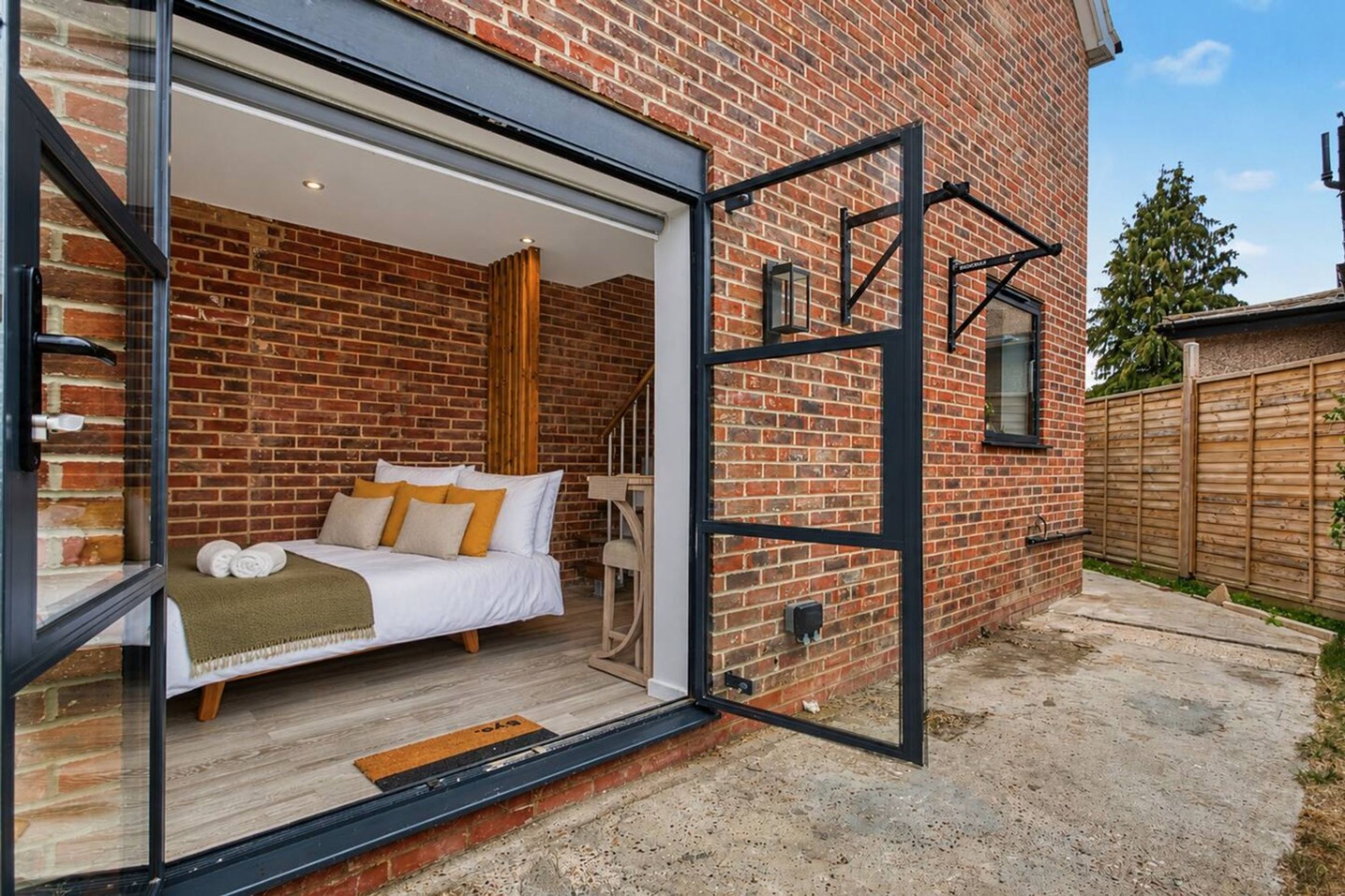 A bedroom with a bed, a wooden floor, and a brick wall.