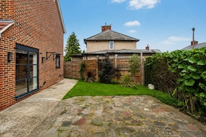 A brick house with a stone patio and a small garden. - Cosy London Studio Free Parking Sleeps 3 (Morden)