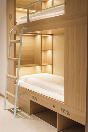 Un lit superposé avec une échelle, un espace de rangement pour les chaussures et une petite étagère.