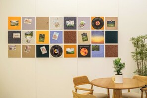 Un mur composé d’une grille de panneaux carrés, dont certains présentent des photographies et un autre un disque vinyle.