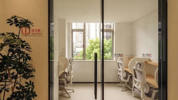 Un salón de estudio con dos sillas, un escritorio, un amplio ventanal y una planta.