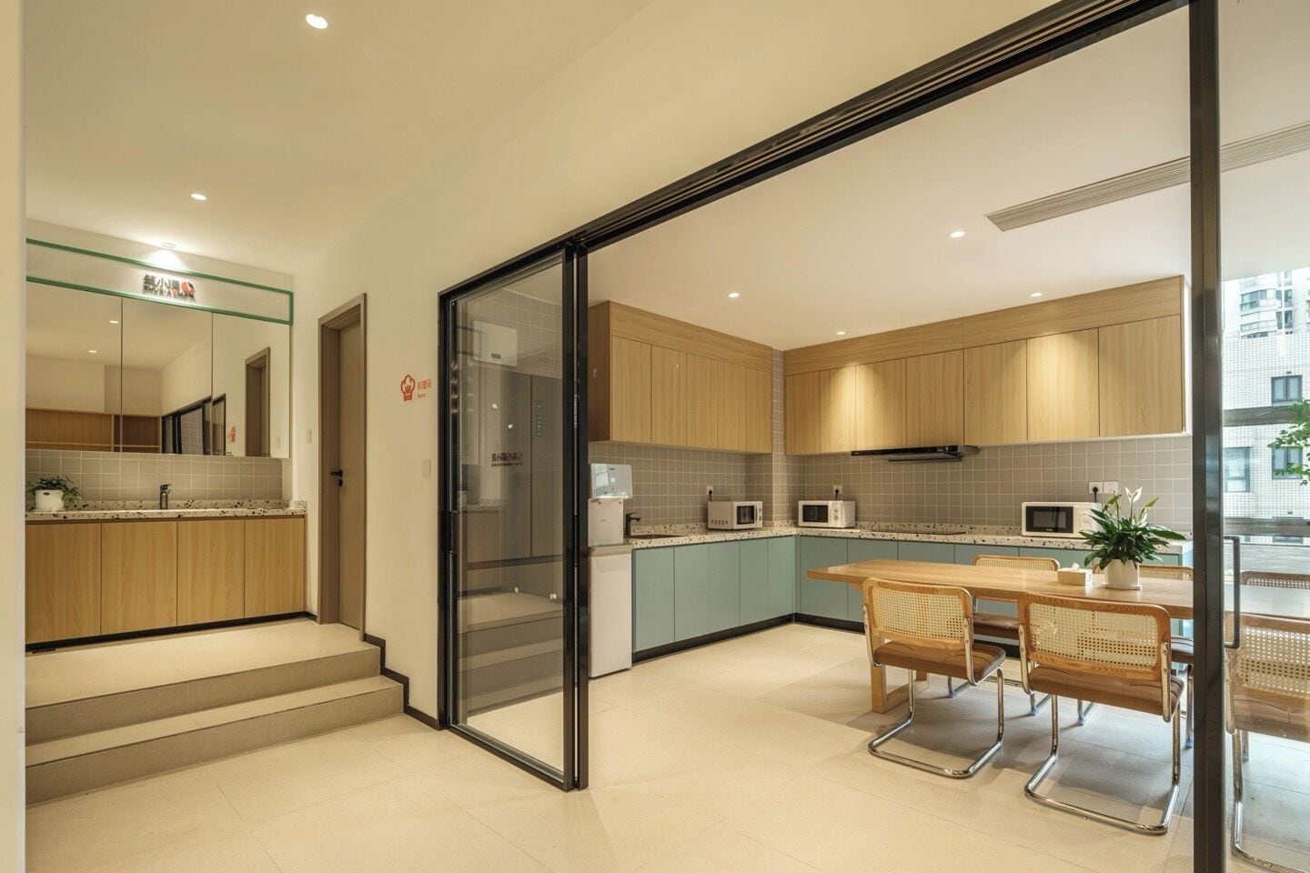 A modern kitchen with wooden cabinets, a glass door entrance, and a dining area with a table and chairs.