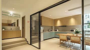 A modern kitchen with wooden cabinets, a glass door entrance, and a dining area with a table and chairs.