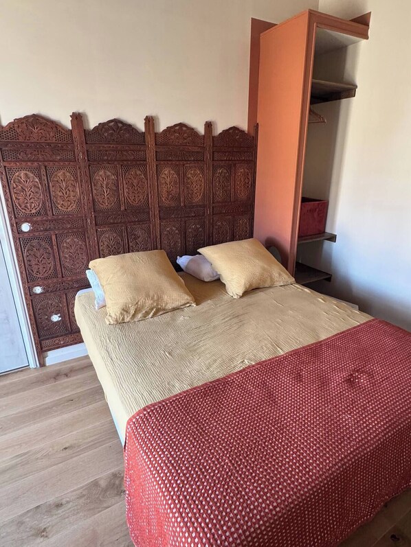 A bed with a wooden headboard, two pillows, and a red blanket.