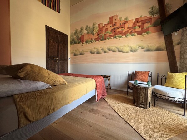 Une chambre à coucher comprenant un lit, une chaise, une petite table et une fresque murale.