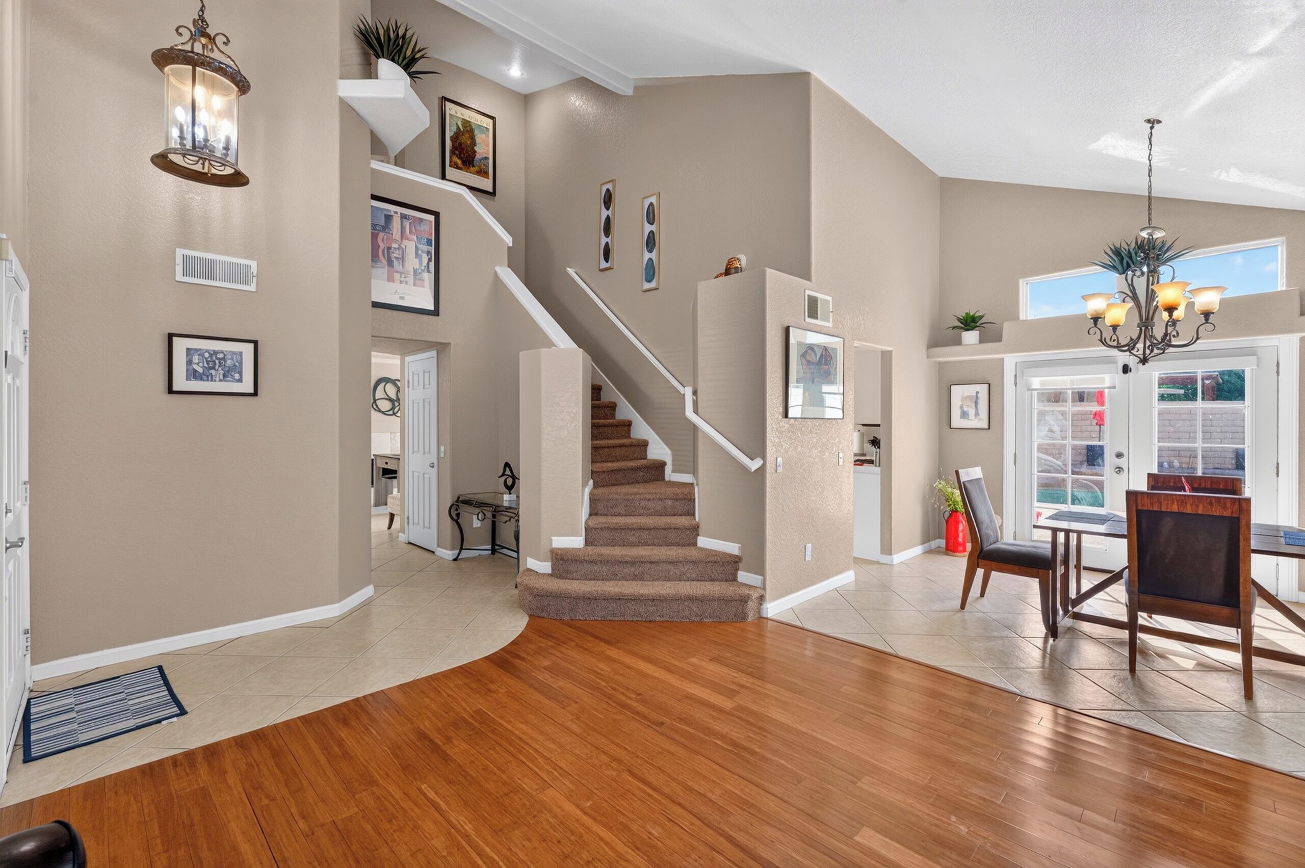 Un intérieur spacieux avec un plancher en bois, un escalier et un coin repas comprenant une table et des chaises.