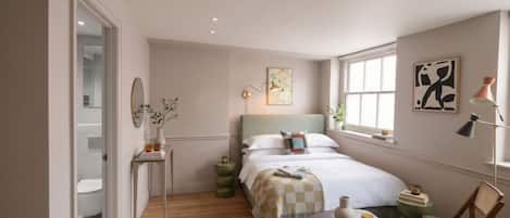 Un dormitorio con cama, mesita de noche, silla y ventana.
