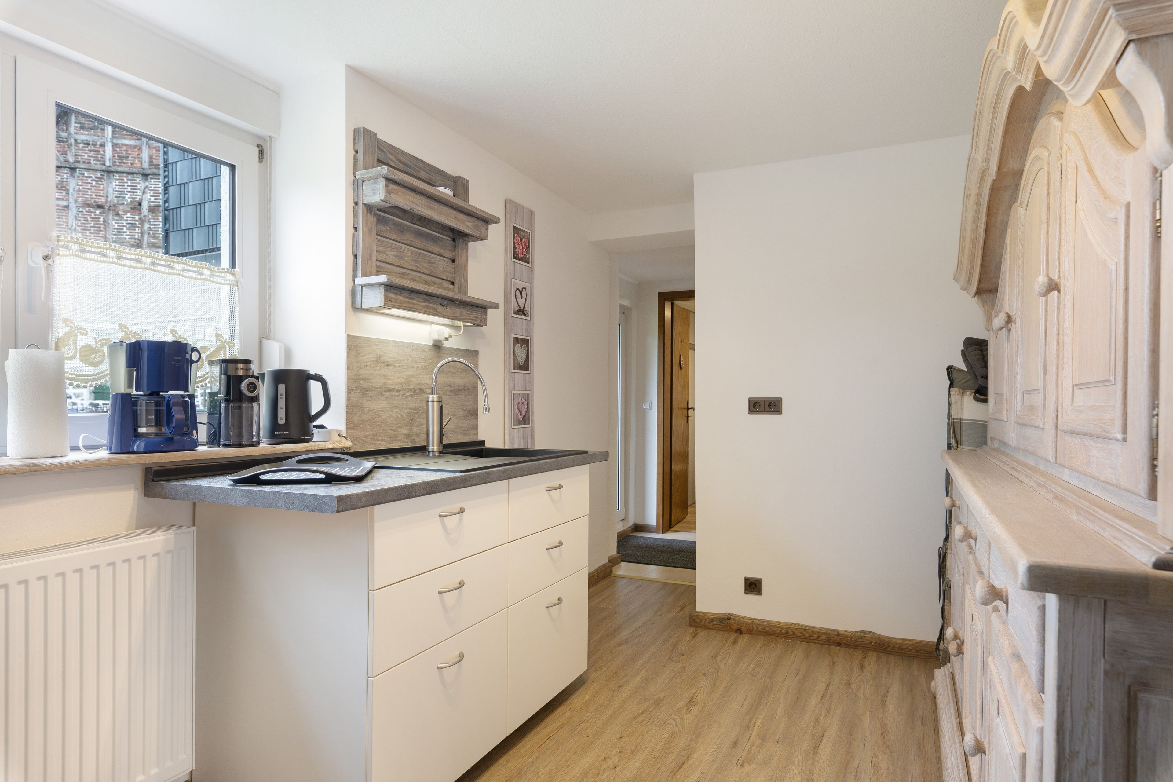 A modern kitchen with a built-in stove, a coffee maker, and a kettle on the counter.