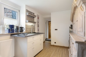 A modern kitchen with a built-in stove, a coffee maker, and a kettle on the counter.
