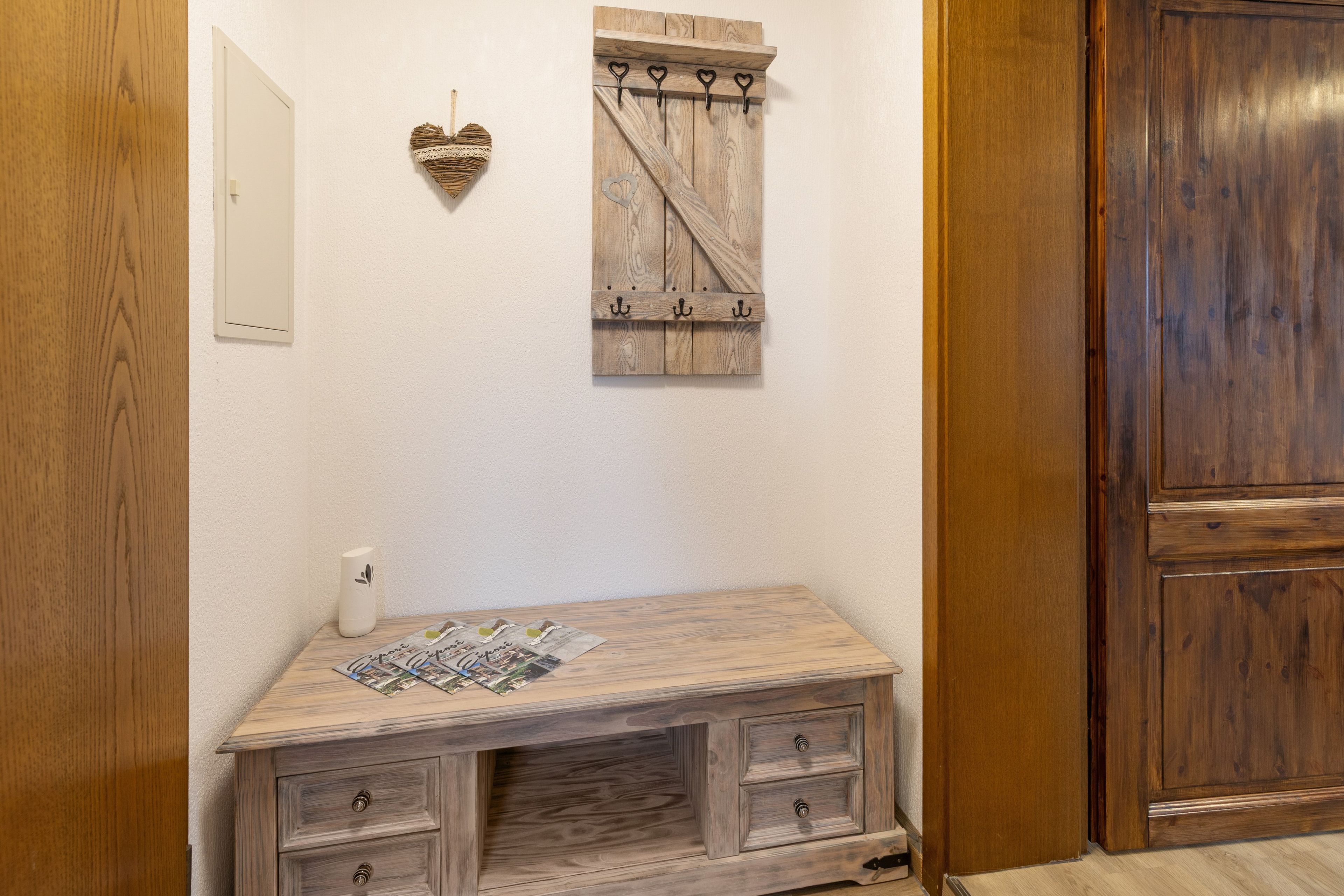 Eine Holzkabine mit Schubladen und einer kleinen Ablage, eine herzförmige Dekoration an der Wand und eine Holztür.