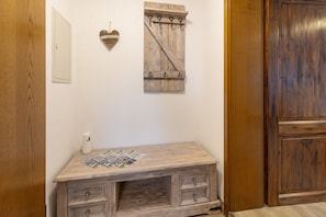 Un mueble de madera con cajones y un pequeño estante, una decoración con forma de corazón en la pared, y una puerta de madera.